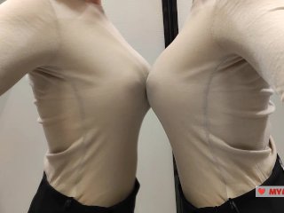 Примерка свитеров в примерочной. Большегрудая красавица натягивает одежду. Вид снизу во время примерки